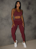 model leaning on a wall wearing the Shimmer V Back Leggings in Ruby star color
