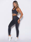 left side profile view of a model wearing the Shimmer V Back Leggings in Black star color