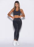 front profile view of a model with both hands on her waist wearing the Shimmer V Back Leggings in Black star color