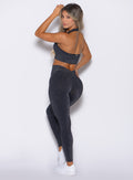back left side profile view of a model looking over her shoulder wearing the Shimmer V Back Leggings in Black star color