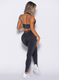 back profile view of a model wearing the Shimmer V Back Leggings in Black star color paired with the matching bra