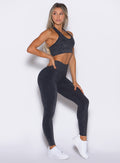 right side profile view of a model  looking to the back side wearing the Shimmer V Back Leggings in Black star color