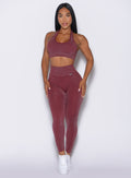 front profile view of a model with both hands resting on her thighs wearing the Shimmer V Back Leggings in Ruby star color