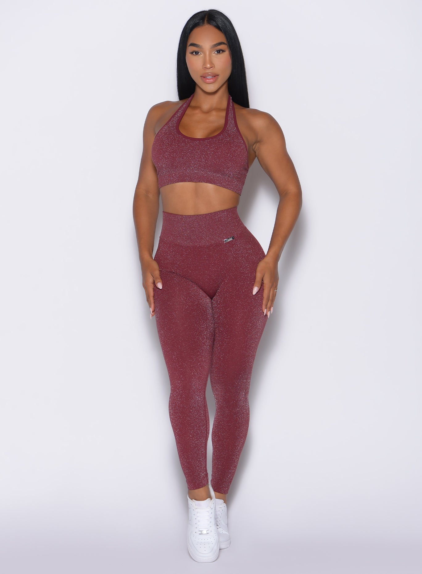 front profile view of a model with both hands resting on her thighs wearing the Shimmer V Back Leggings in Ruby star color