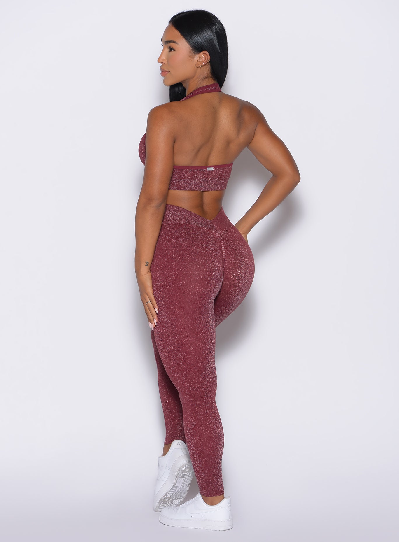back left side profile view of a model wearing the Shimmer V Back Leggings in Ruby star color