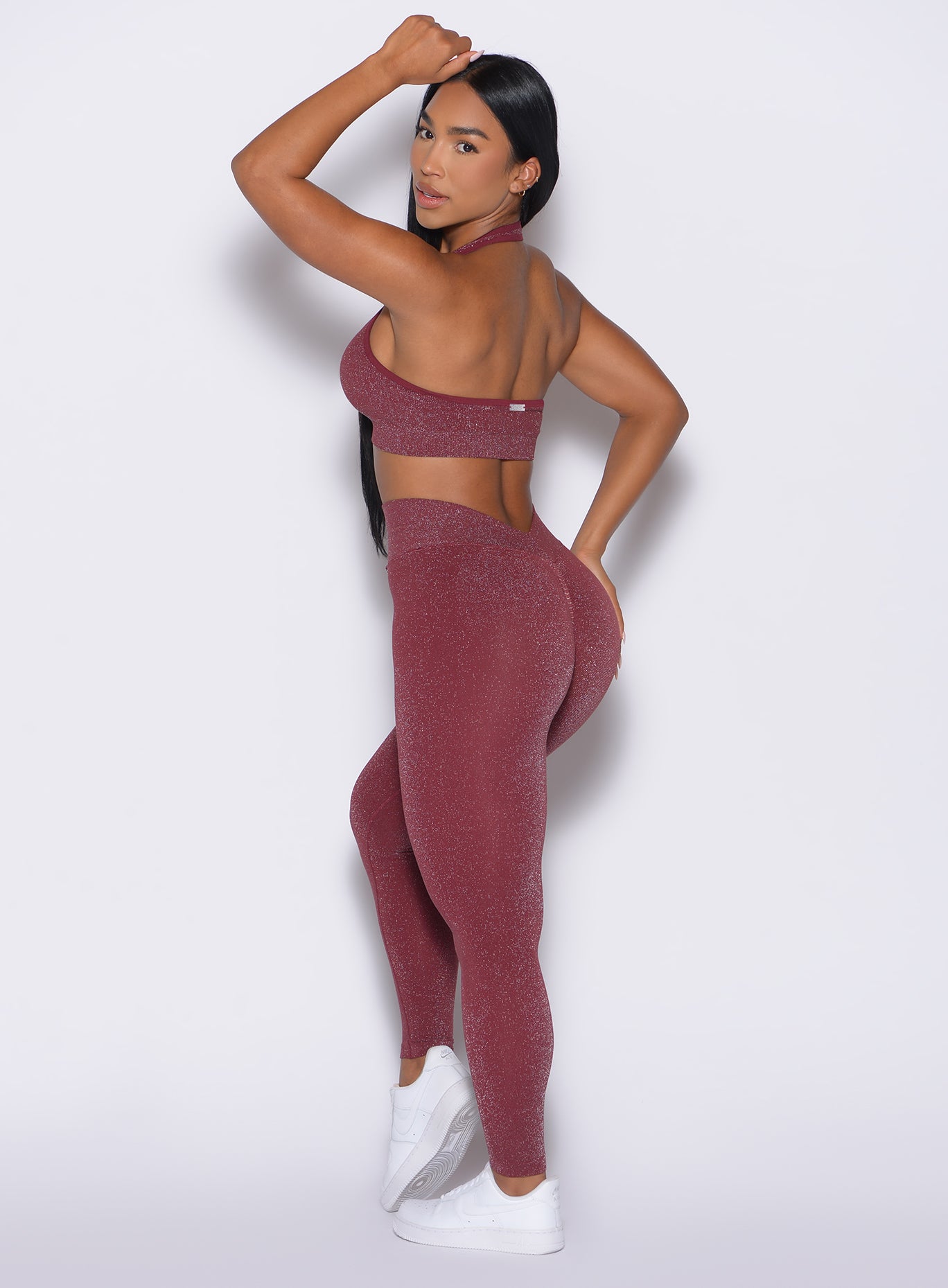 back left side profile view of a model looking over her shoulder wearing the Shimmer V Back Leggings in Ruby star color