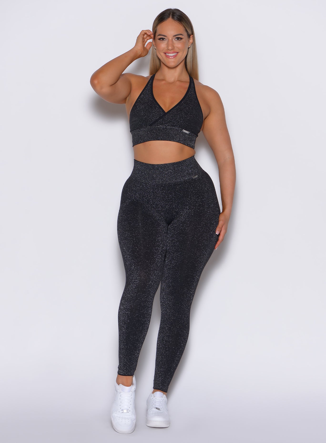 front profile view of a model wearing our Shimmer Seamless Leggings in black sparkle color along with the matching bra