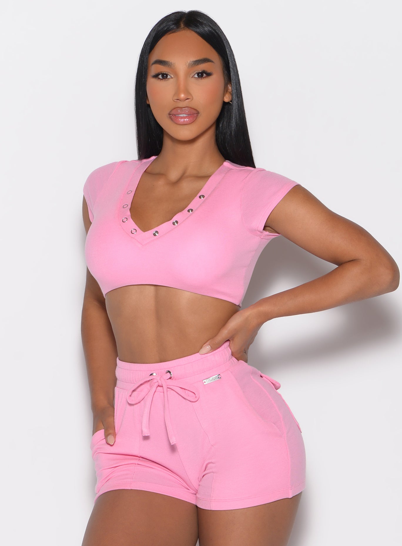 front profile view of a model with one hand on her waist wearing the Snap Top in Pink Cupcake color pared with the matching shorts