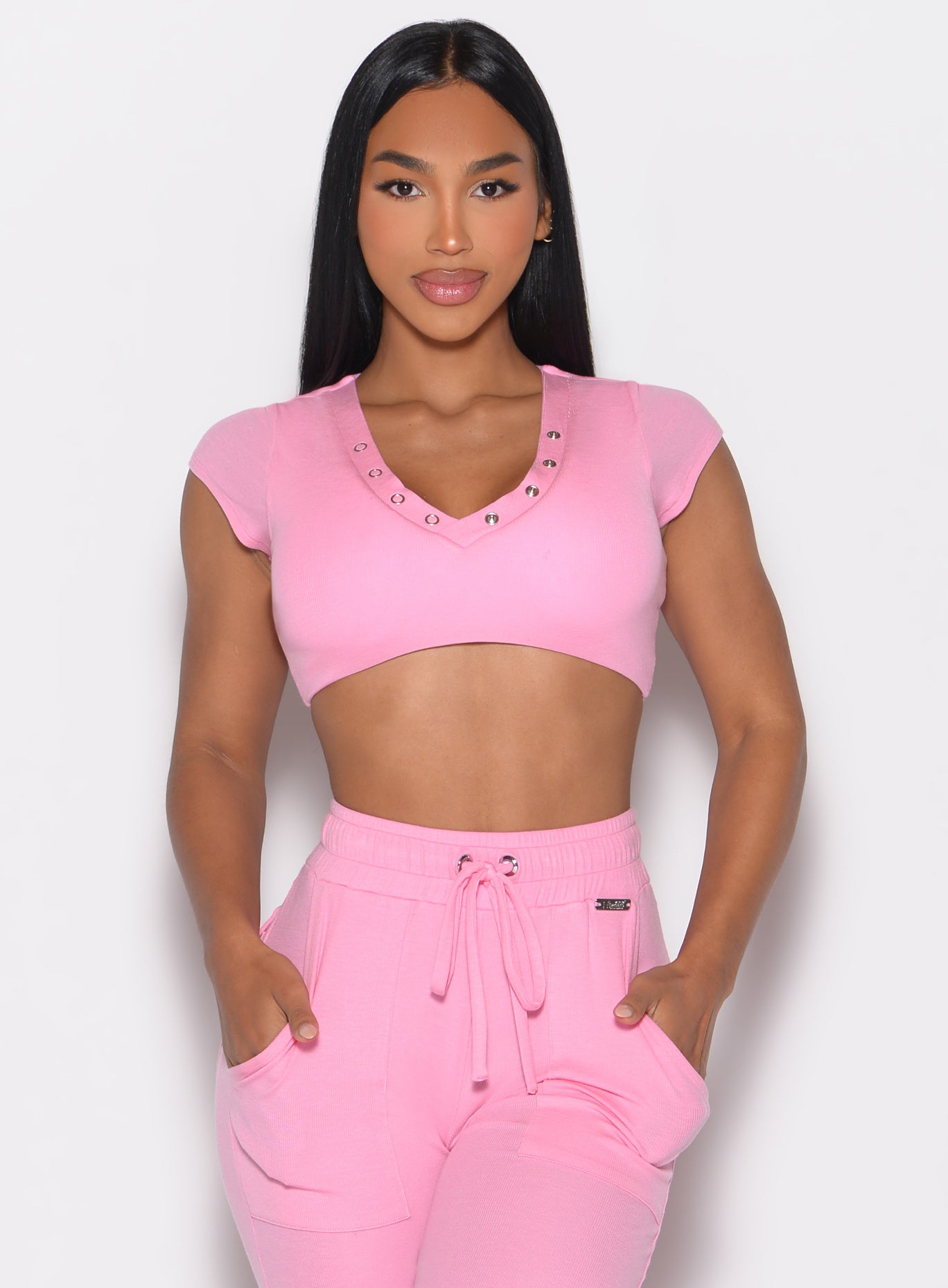 front profile view of a model with both hands inside the pockets of the matching joggers wearing the Snap Top in Pink Cupcake color