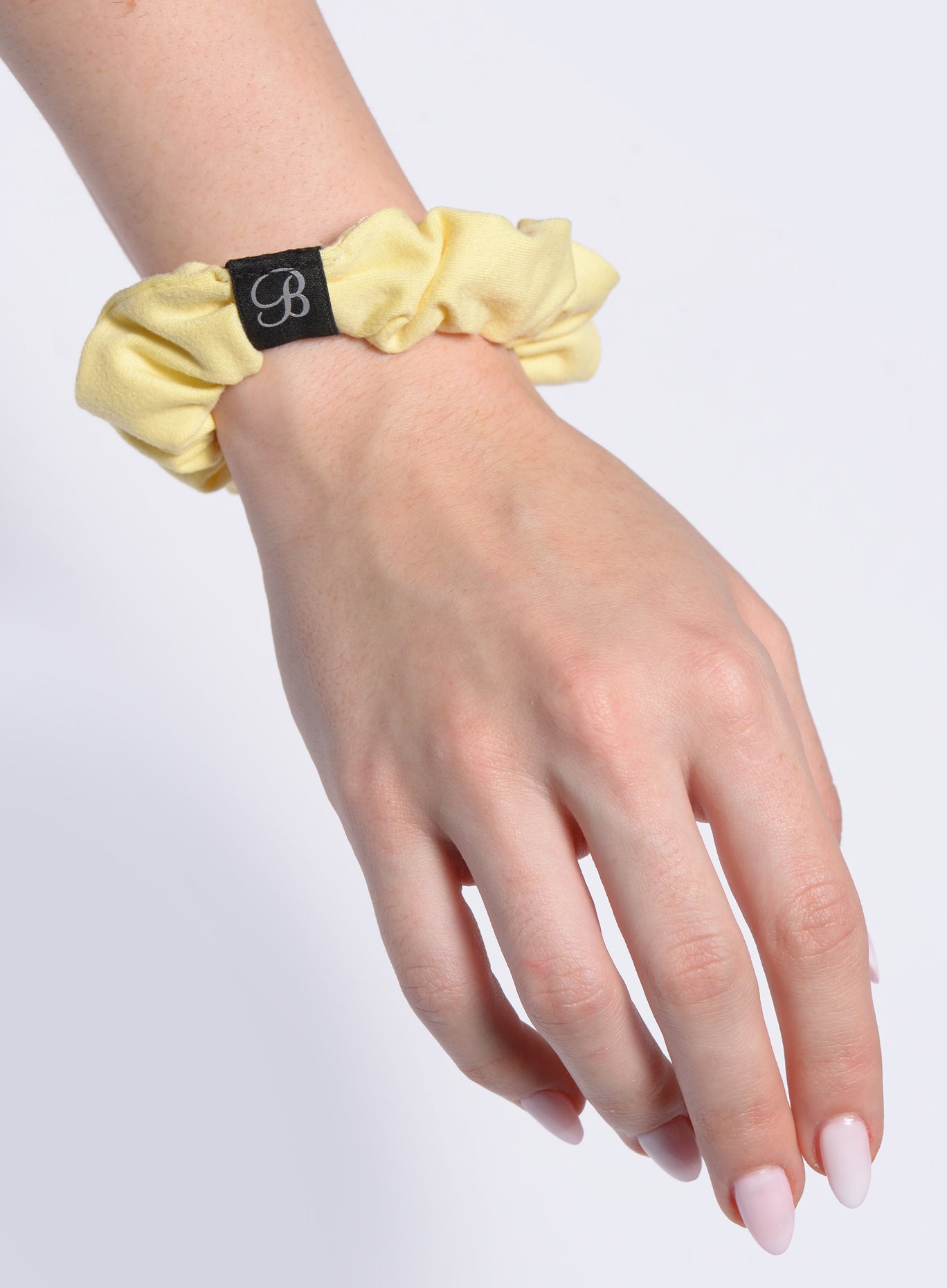 close up picture of the B Scrunchie in Soft Yellow color on a hand