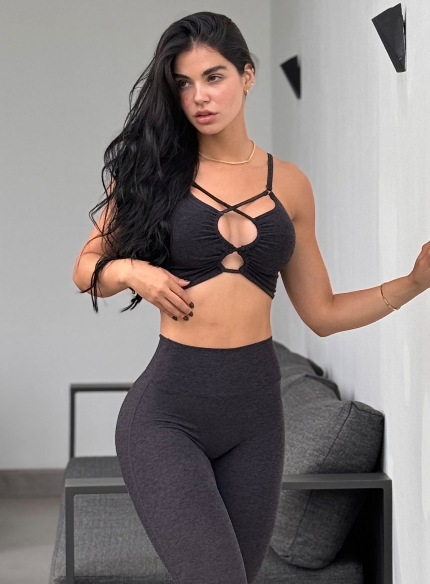 front profile view of a model wearing our black loop luxe bra top along with the matching leggings
