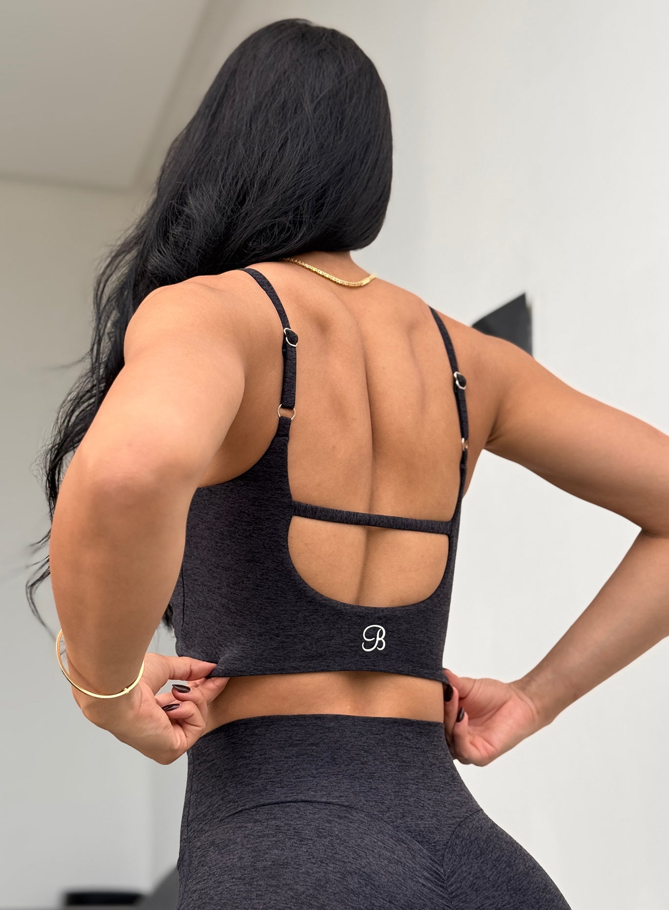 Back view of the Heathered Black Loop Luxe Bra Top featuring a strappy and detailed back design.