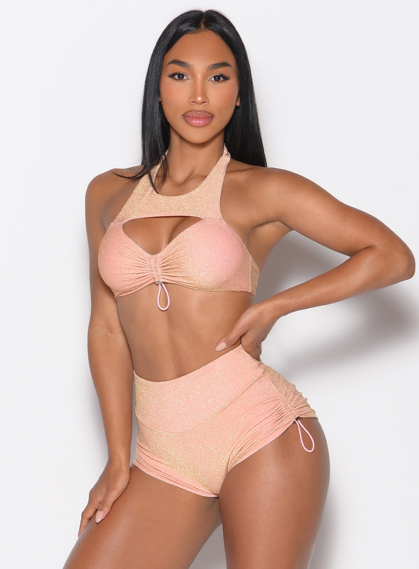 front profile view of a model with her left hand on her waist wearing the Sunkissed Sparkle Bikini Bra in Golden Hour color