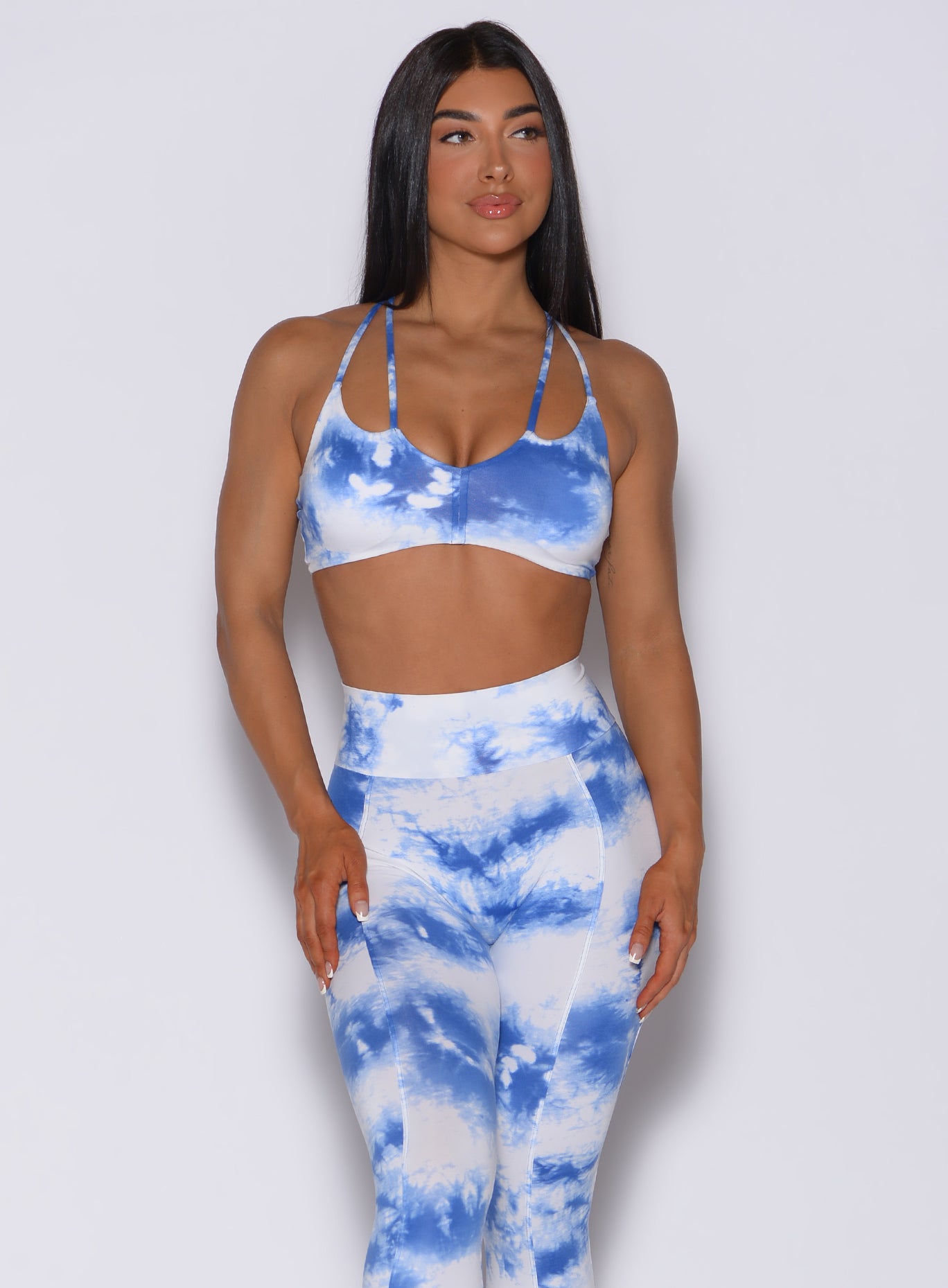 Picture of a model facing forward wearing our tie dye topnotch bra in white blue along with a matching leggings