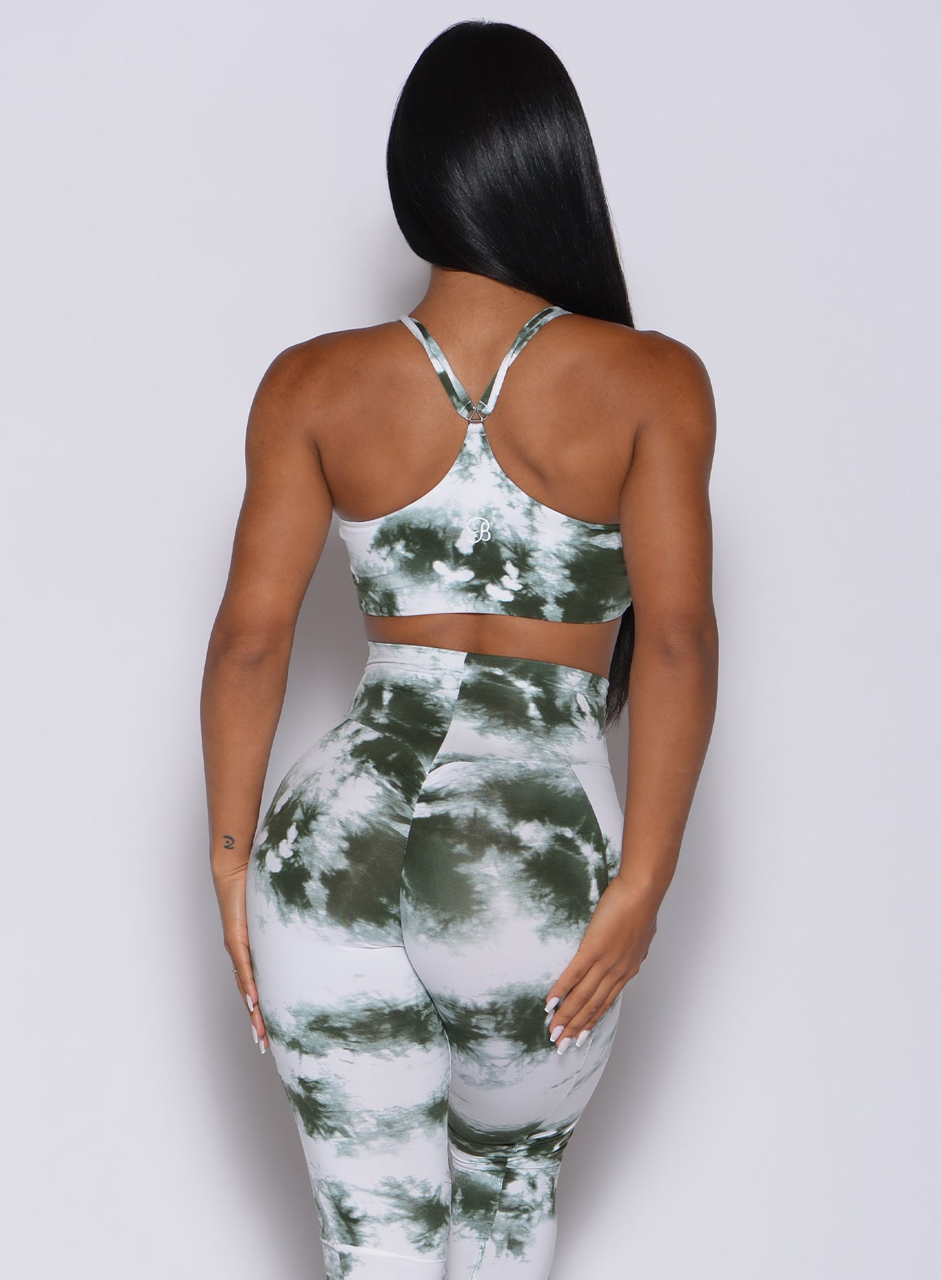 Back profile view of a model in our topnotch bra in tie dye white green color and a matching leggings
