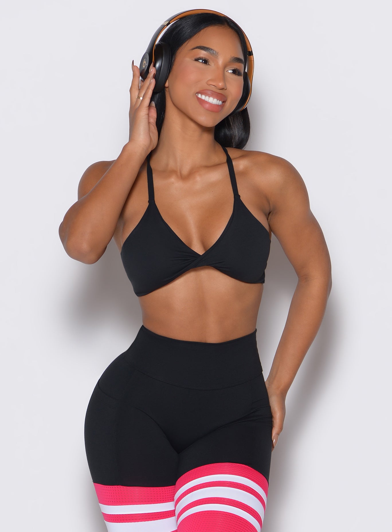 Front profile view of a model with her headphones on wearing our Twist Mini Bra in Fire color complemented by a matching thigh high