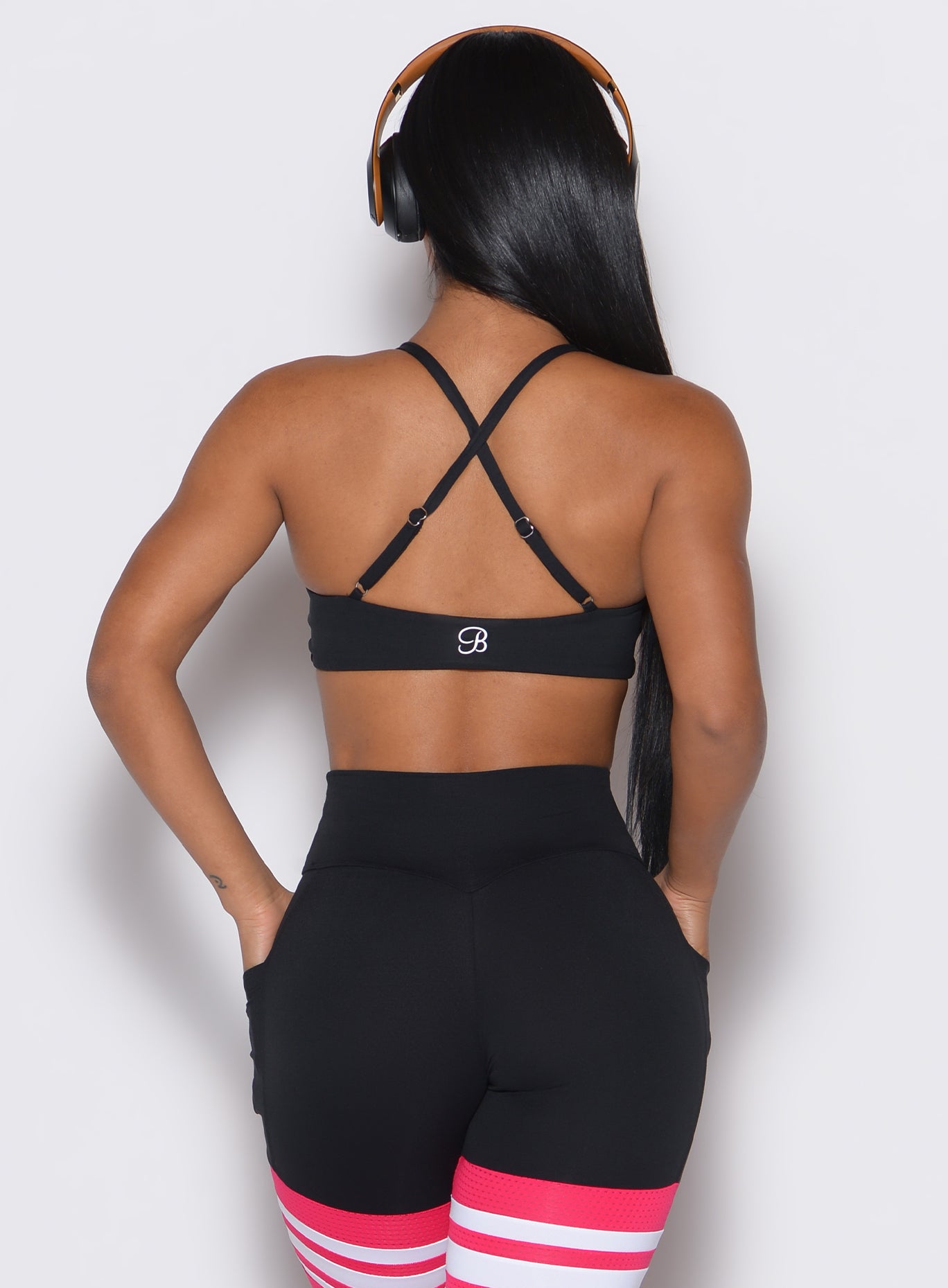 Back profile view of a model wearing our black Twist Mini Bra complimented by a matching thigh high
