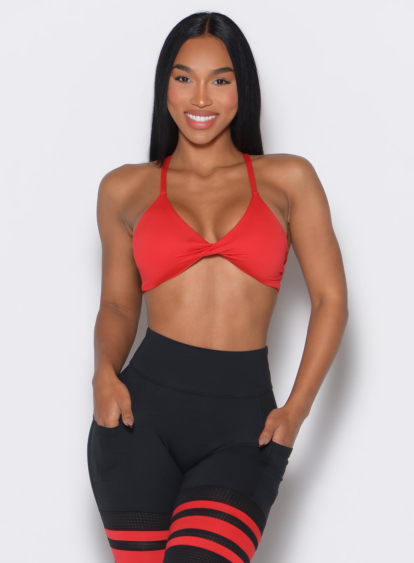 Front profile picture of a model wearing the Twist Mini Bra in Fire color complemented by a matching thigh high
