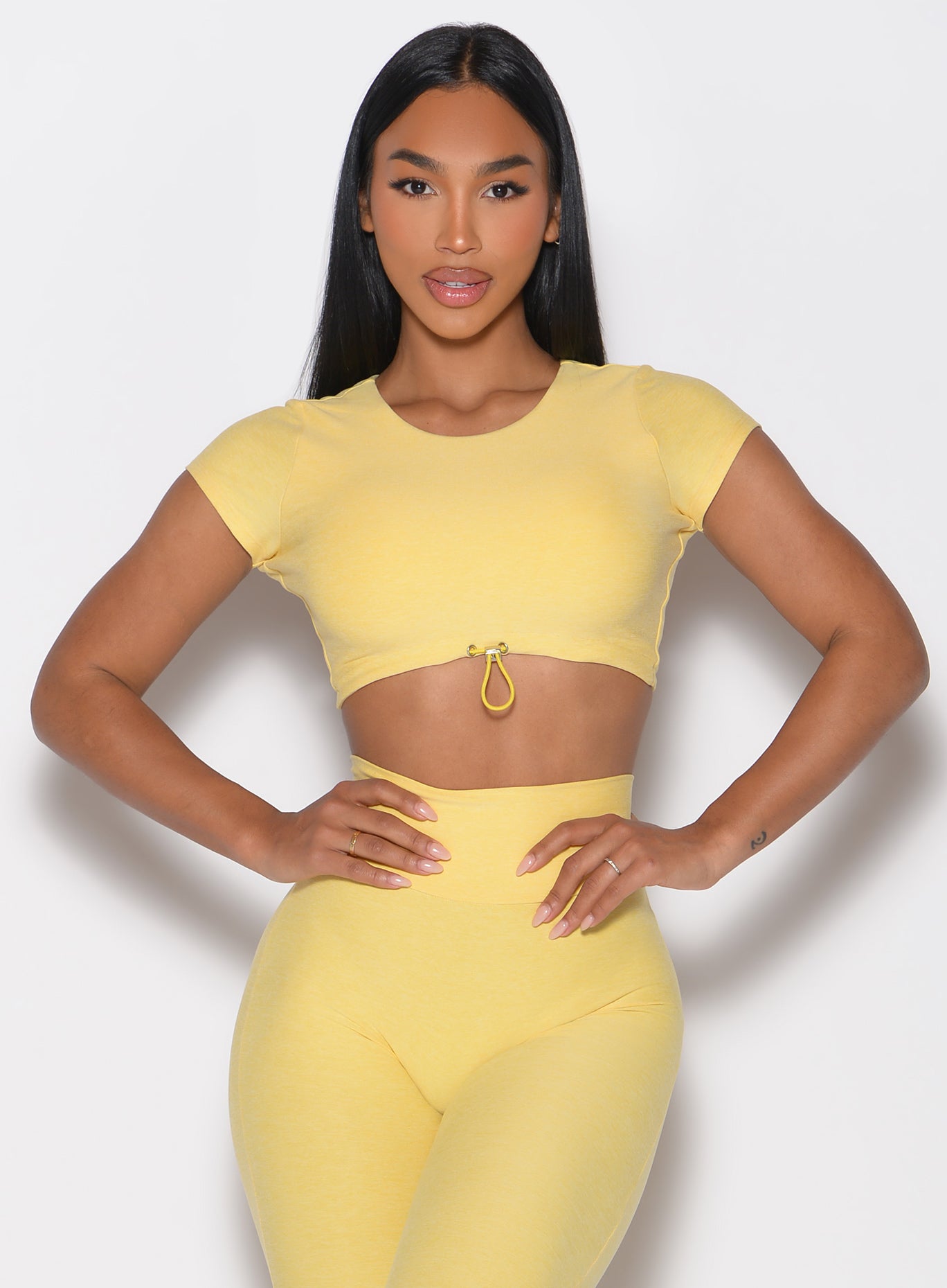 front profile view of a model with both hands on her waist wearing the Toggluxe Tee in Lemon color