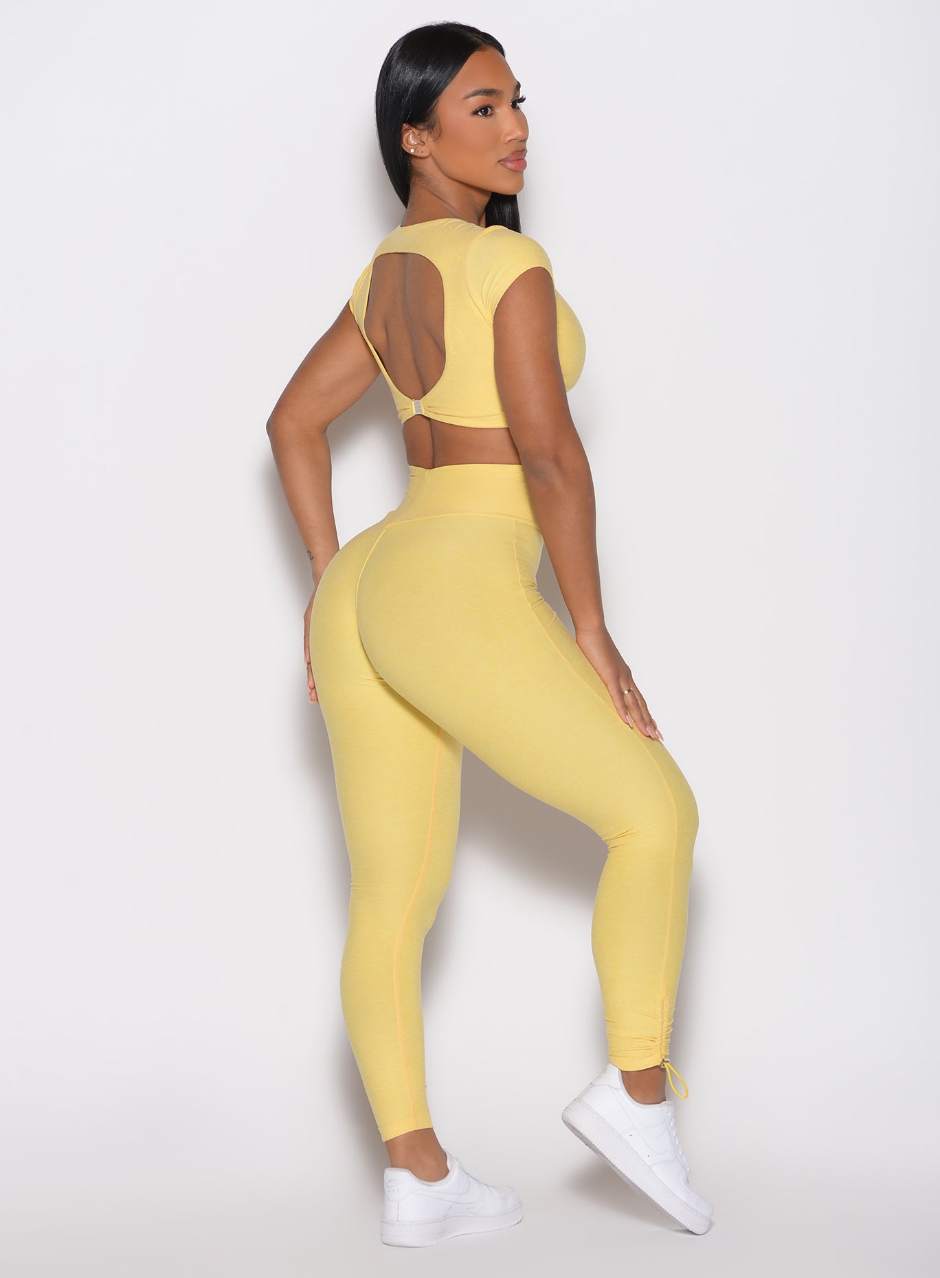 back right side profile view of a model wearing the Toggle Pull Leggings in Lemon color