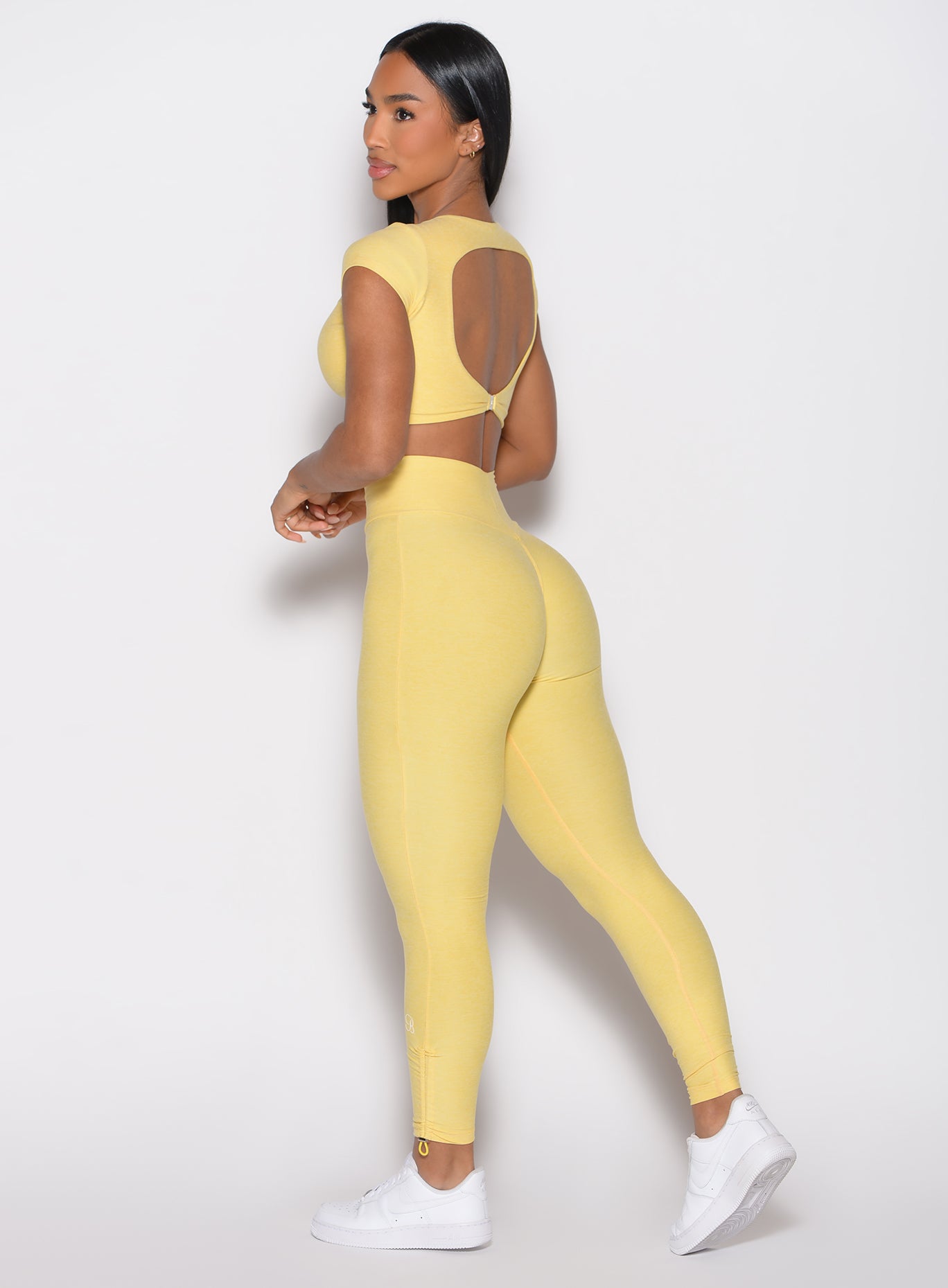 left side profile view model wearing the Toggle Pull Leggings in Lemon color