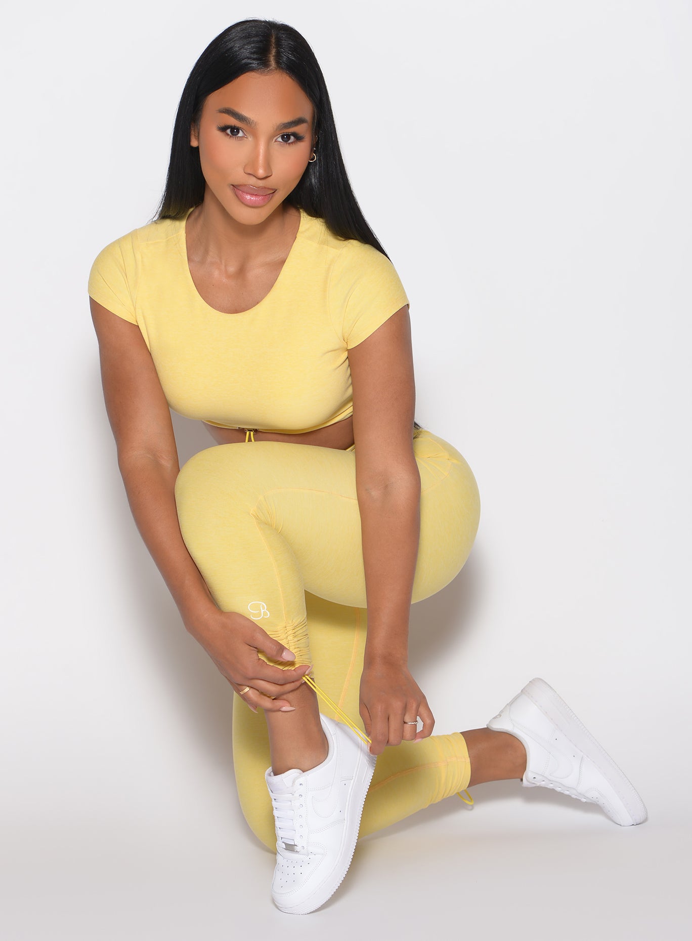 Kneeling pose in Lemon Toggle Pull Leggings featuring an internal scrunch butt for gym lifting.