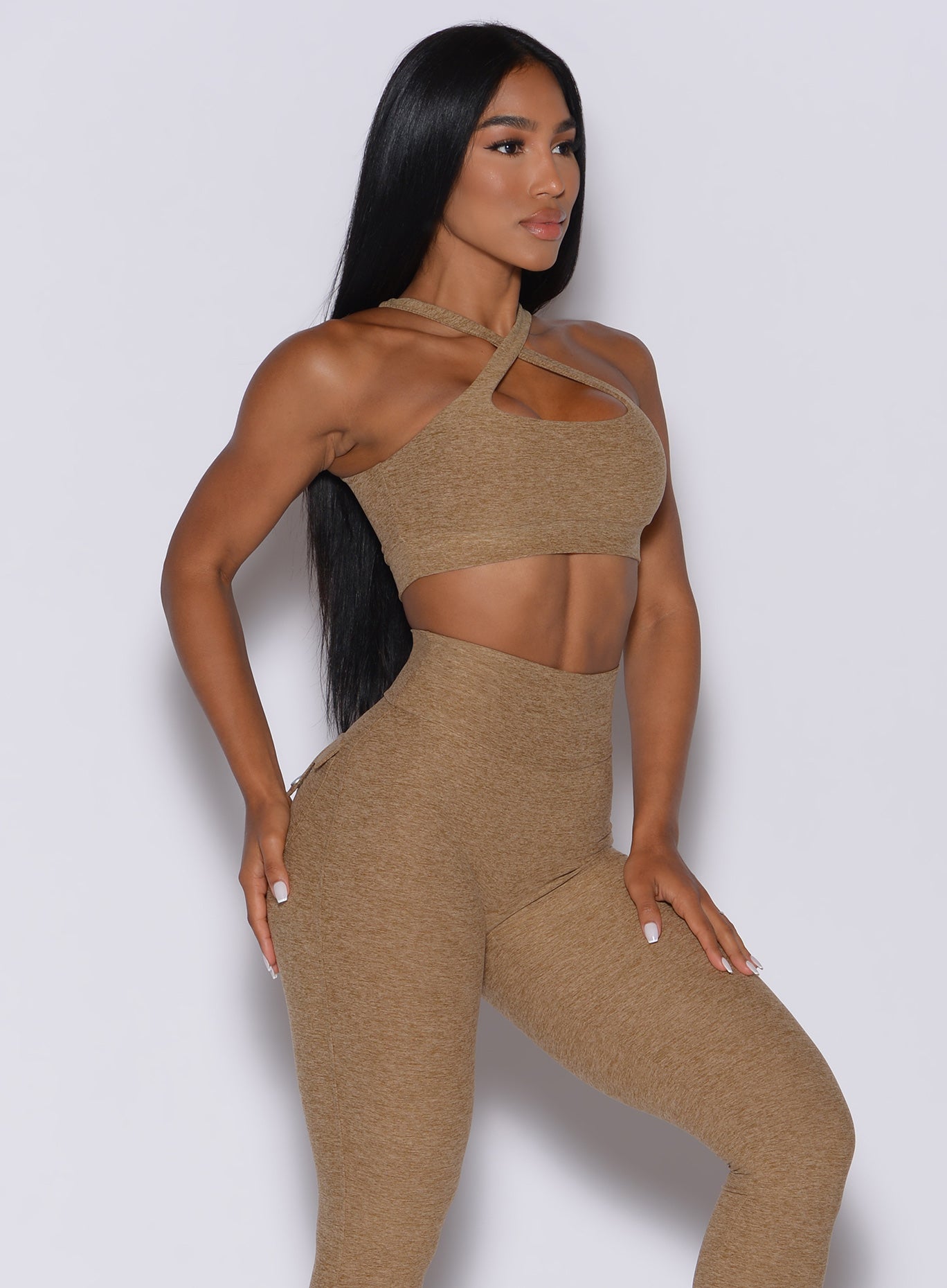 Right side profile view of a model angled slightly to her right wearing our two way sports bra in caramel color and a matching leggings
