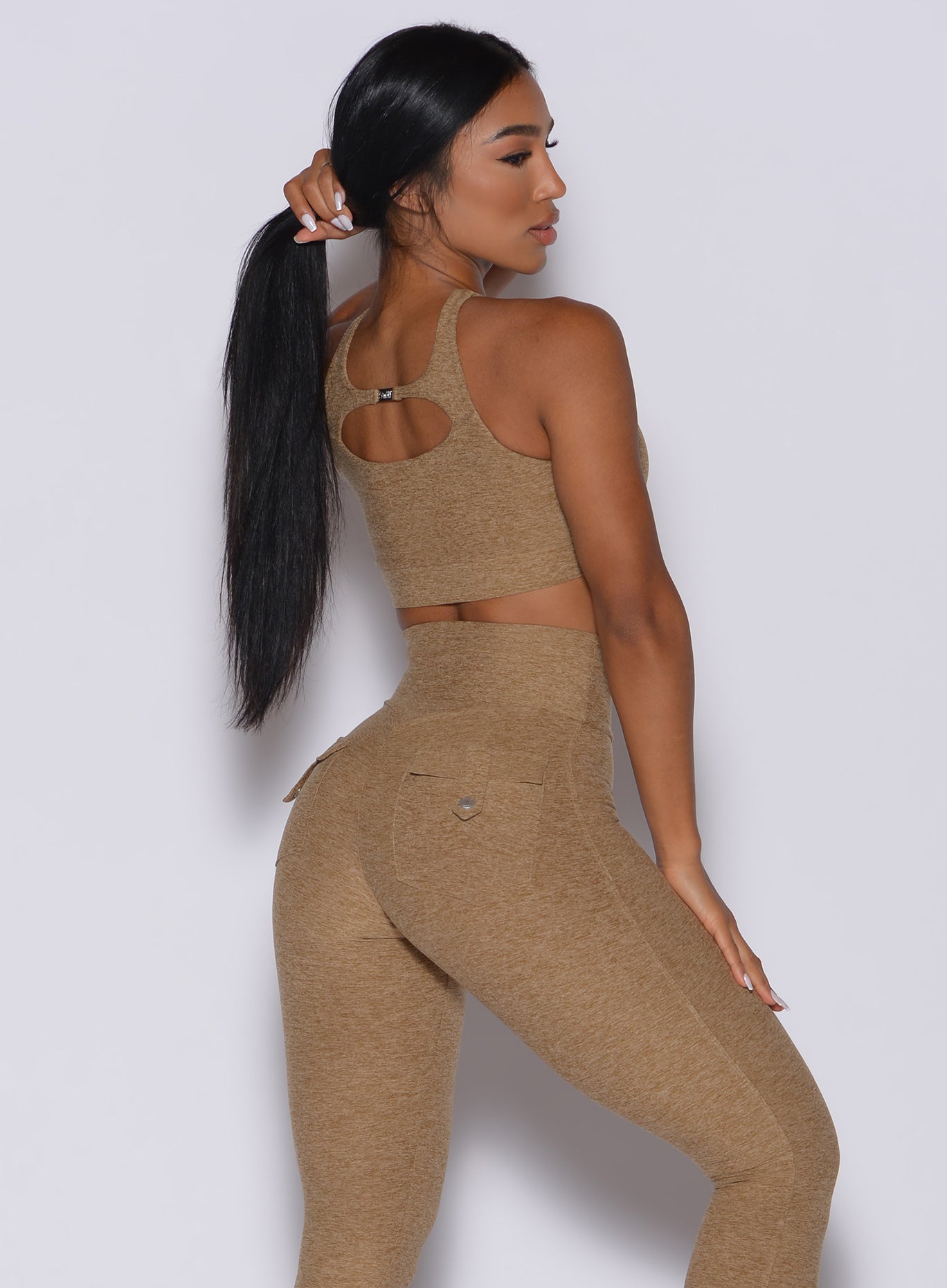 Back profile picture of a model in our two way sports bra in caramel color and a matching leggings