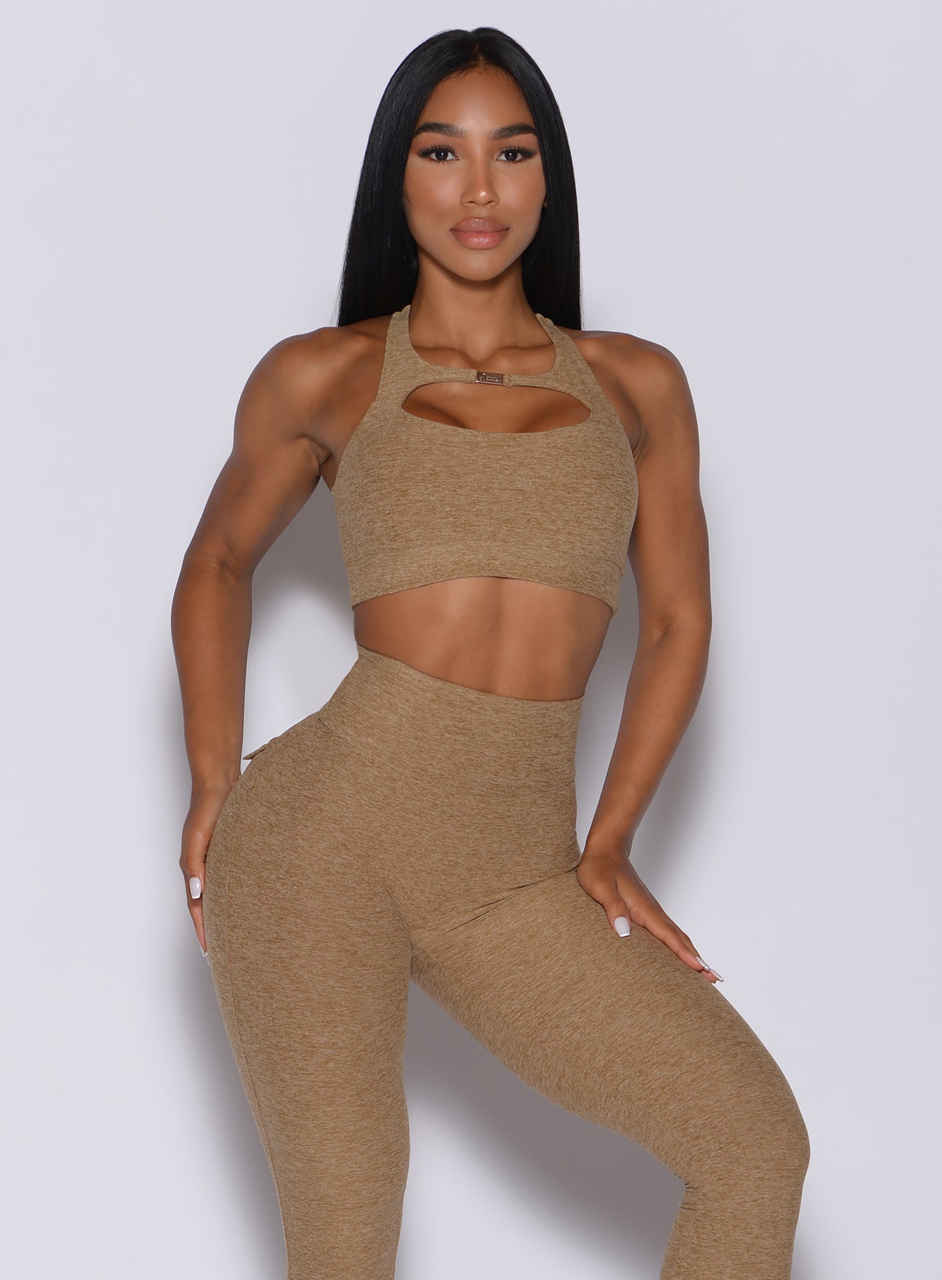Front profile view of a model wearing our two way sports bra in caramel color and a matching leggings