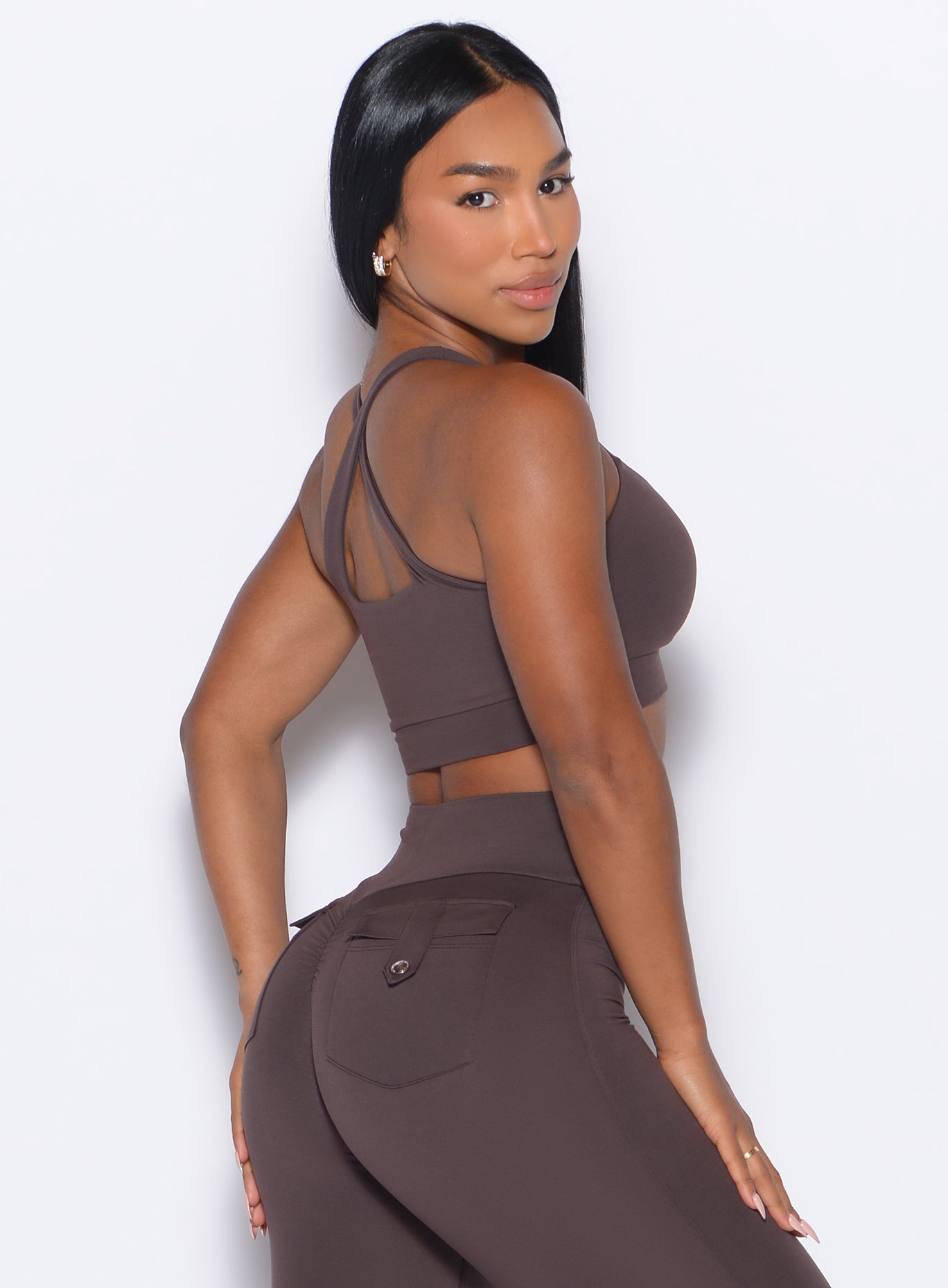 Right side profile view of a model facing to her right wearing our Two Way Bra in Seal Brown color and a matching leggings