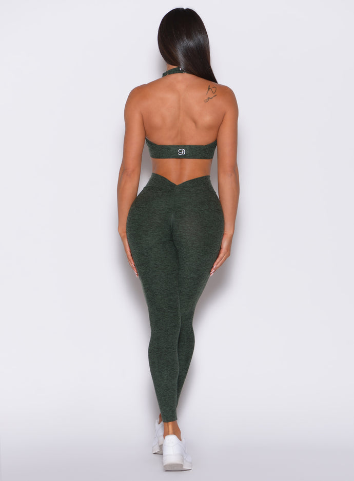 Back profile view of a model in our V Back Leggings in hunter green color along with the matching bra