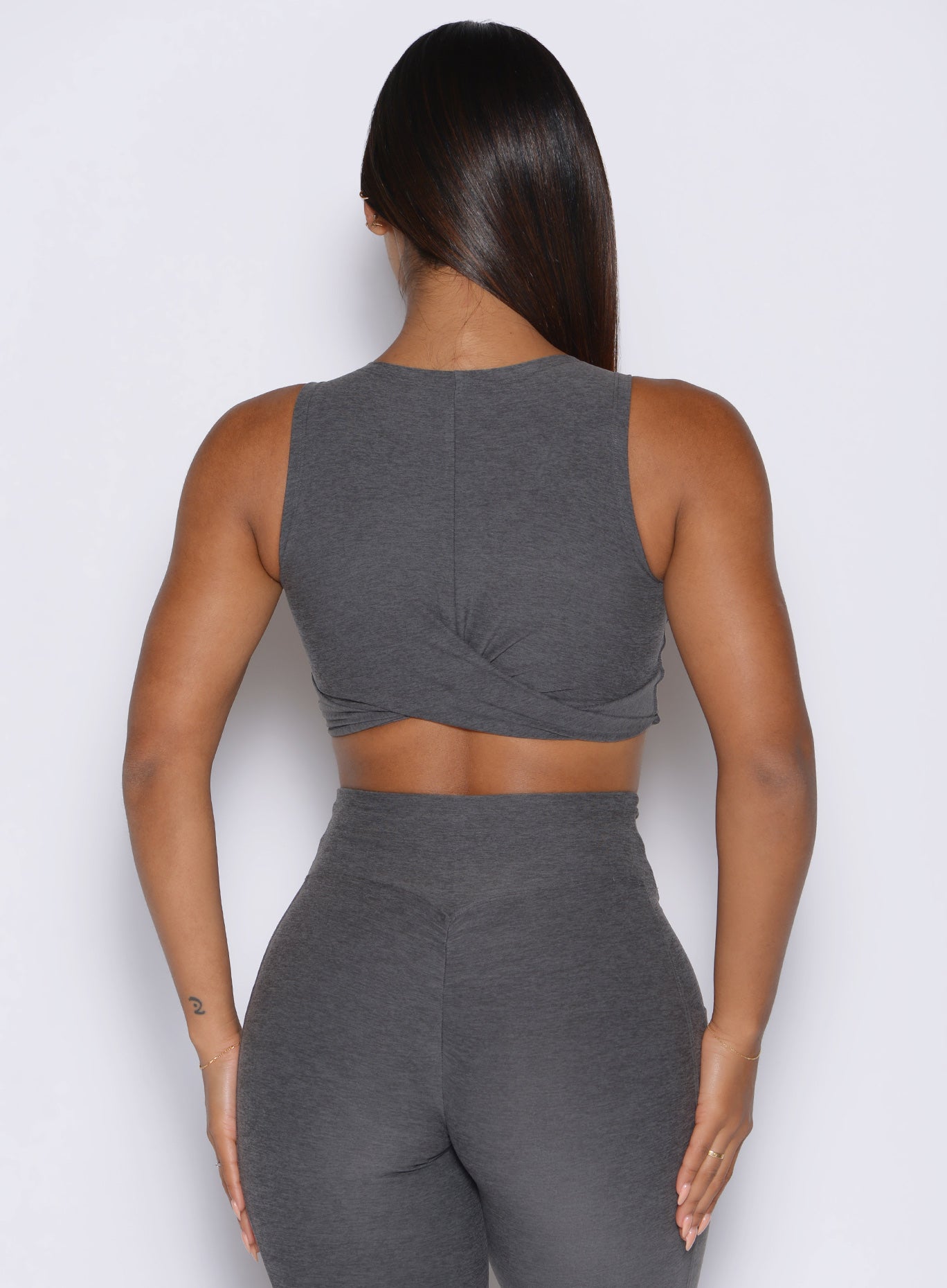 Person wearing a gray sleeveless top and high-waisted leggings against a white background