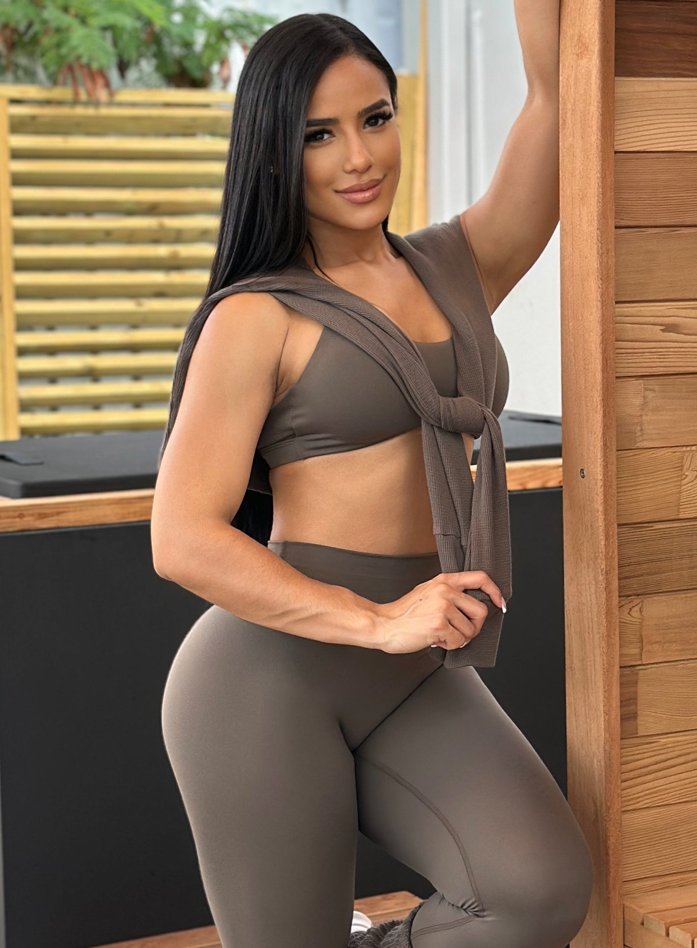 front left side profile view of a model in outdoors with the Allure Pullover in winter Oak color draped over her shoulder