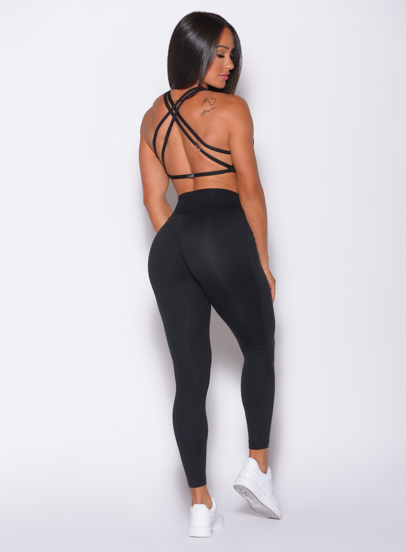 Back profile view of a model in our black barbell leggings and a matching bra