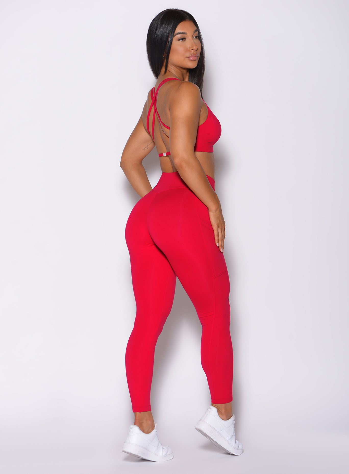 Right side profile view of a model in our red barbell leggings and a matching bra 
