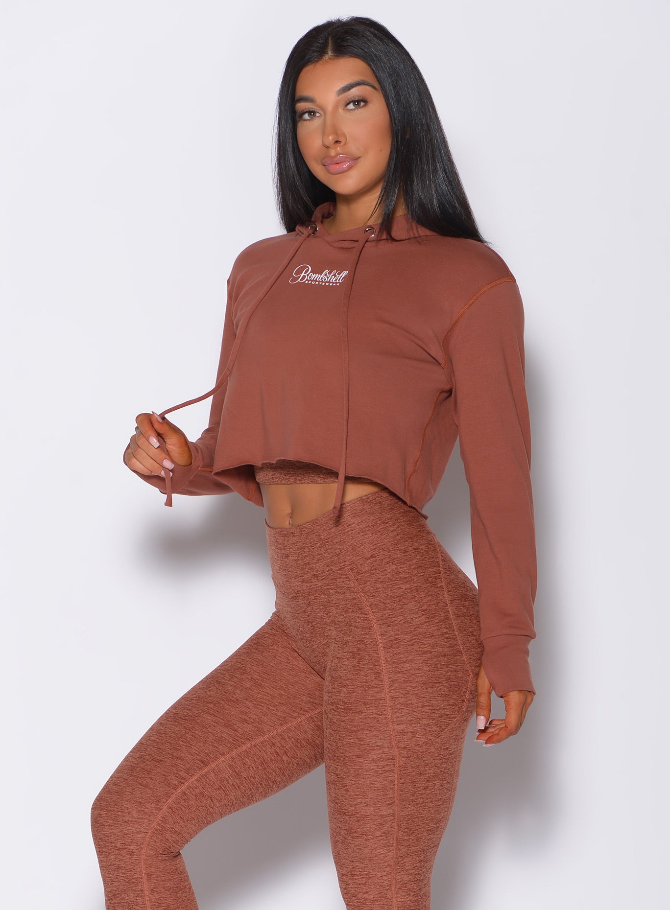 Front profile view of a model wearing our bombshell hoodie in caramel color and a matching leggings