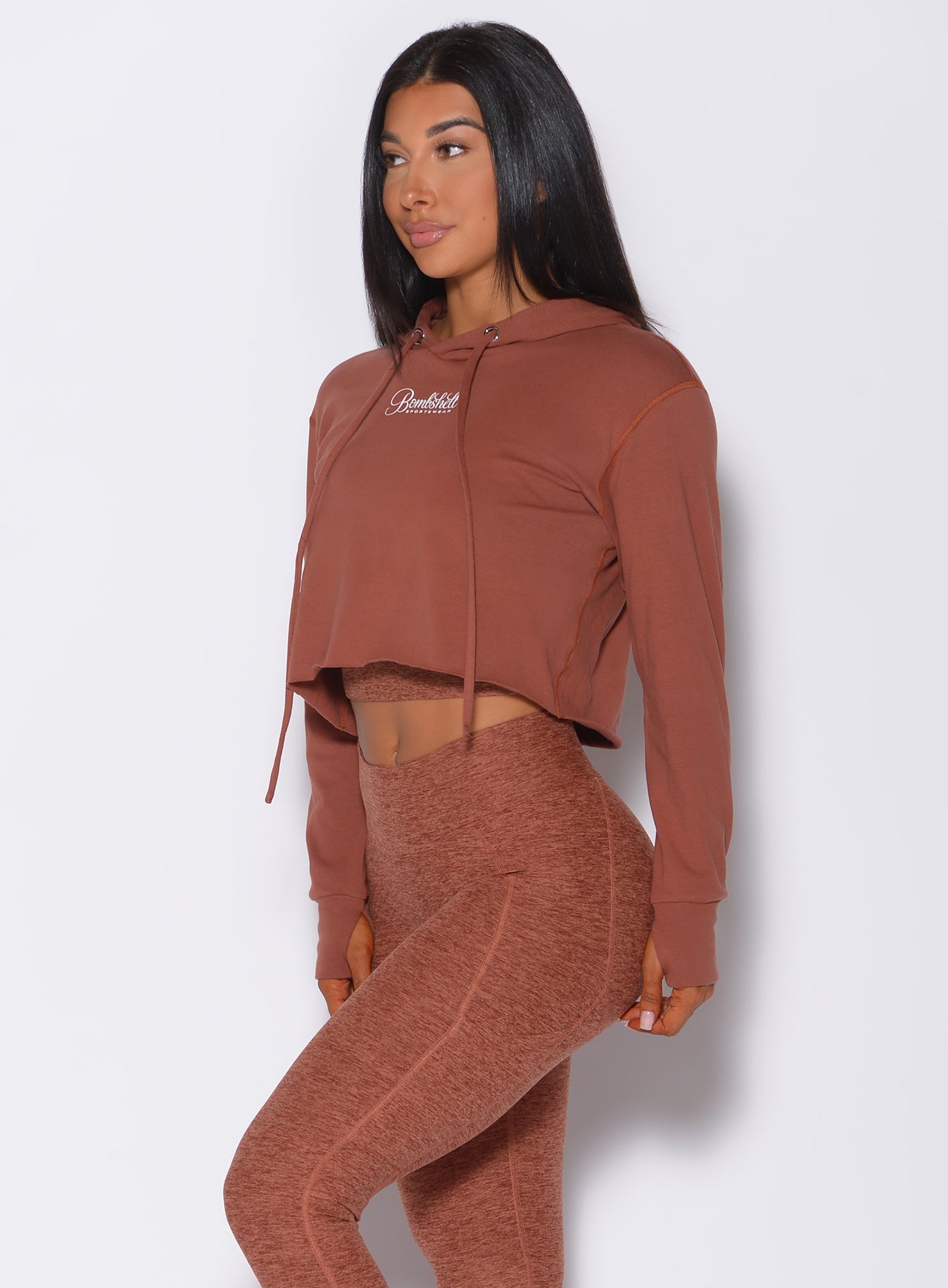 Left side profile view of a model angled left wearing our bombshell hoodie in caramel color and a matching leggings