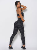 Right side profile of the model in the Fit Camo Leggings in charcoal color.
