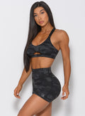 Side profile of the model angled left wearing the camo shorts in charcoal black