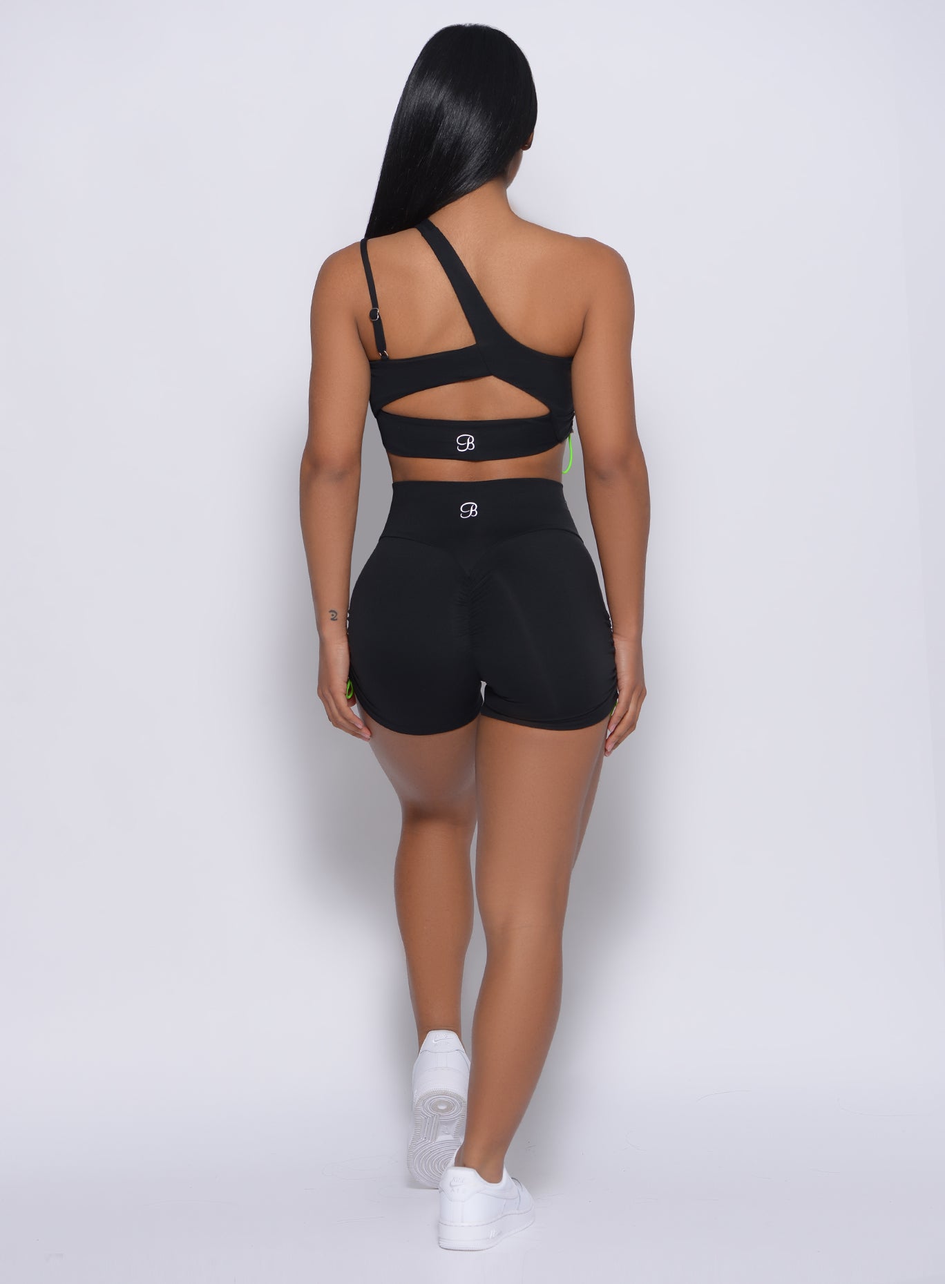 back profile of model wearing the Contour Toggle Shorts in Black color and a matching sports bra
