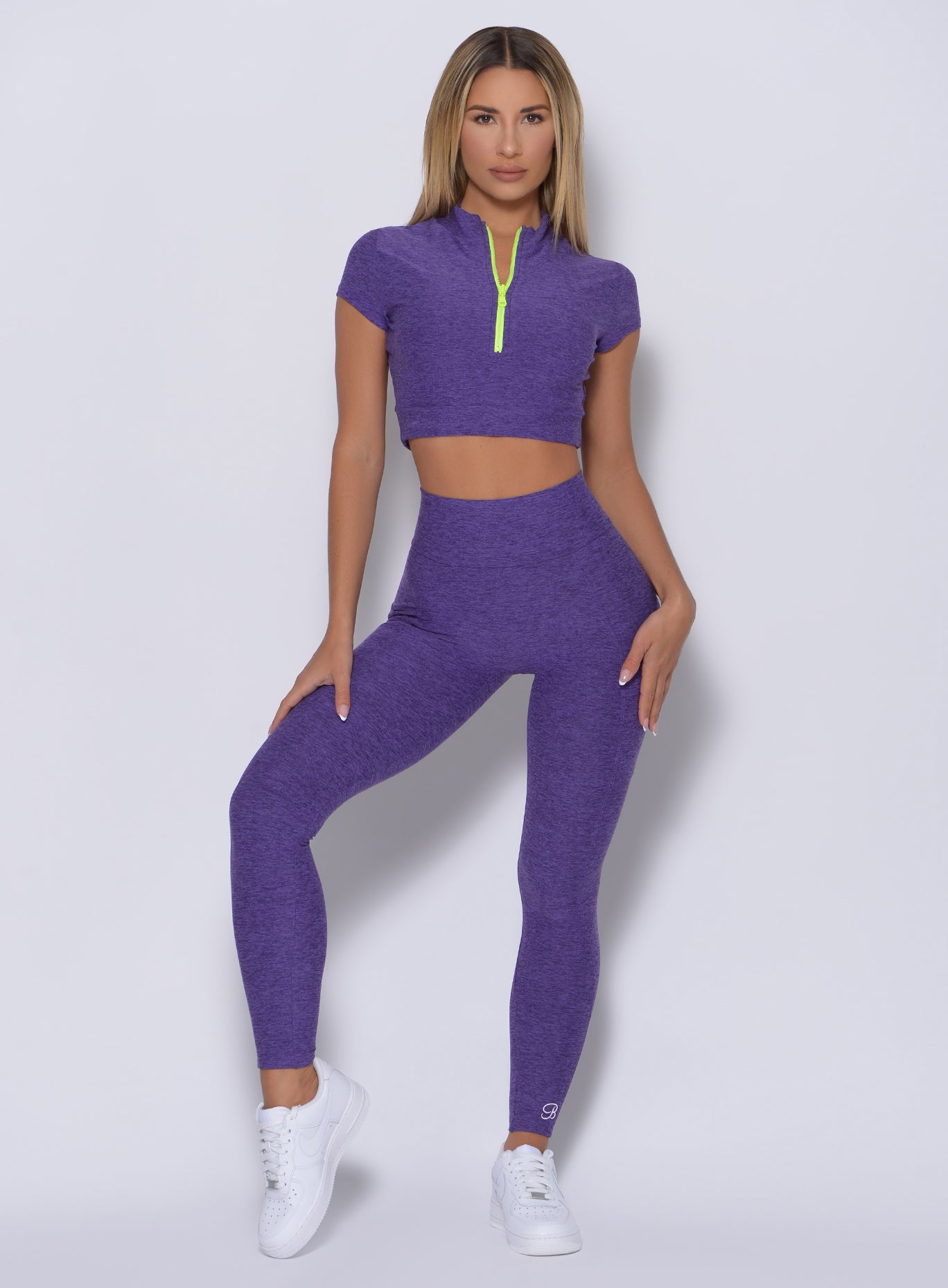 Front profile view of the model with her right hand on thigh wearing our curves leggings in iris color and a matching top