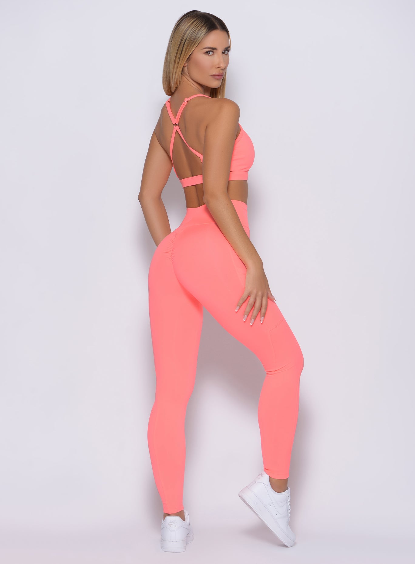 Back profile view of the model in our curves leggings in wild peach color and a matching bra