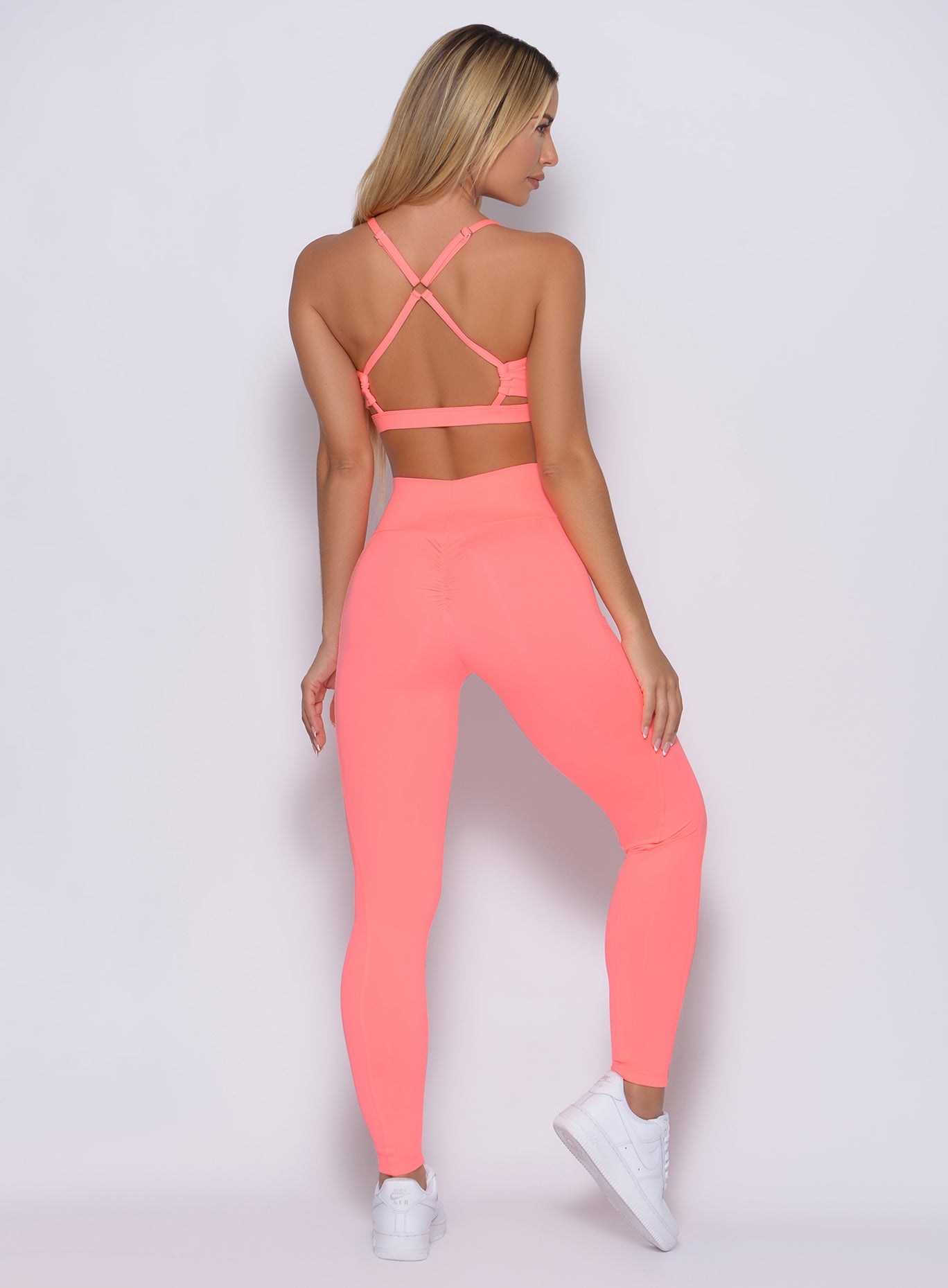 Back profile view of the model wearing our curves leggings in wild peach color and a matching bra