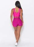 back profile of model wearing the Curves Shorts in Ultra Pink color and a matching Sports Bra