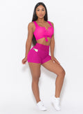 front profile view of a model with her left hand in her left thigh posing in our Curves Shorts in Ultra Pink color and a matching Sports Bra