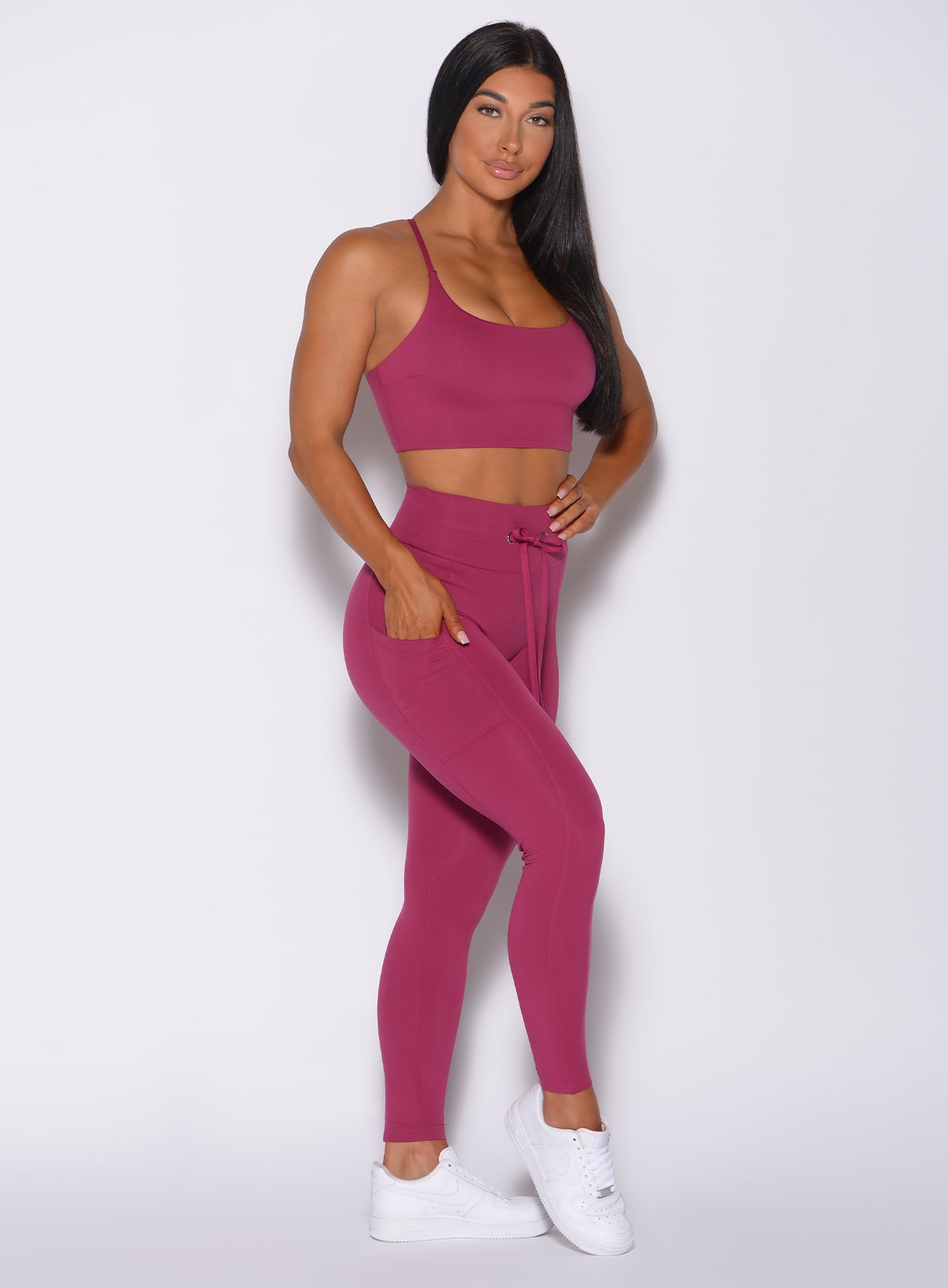Right side profile view of a model angled right wearing our empower leggings in berry good color and a matching bra