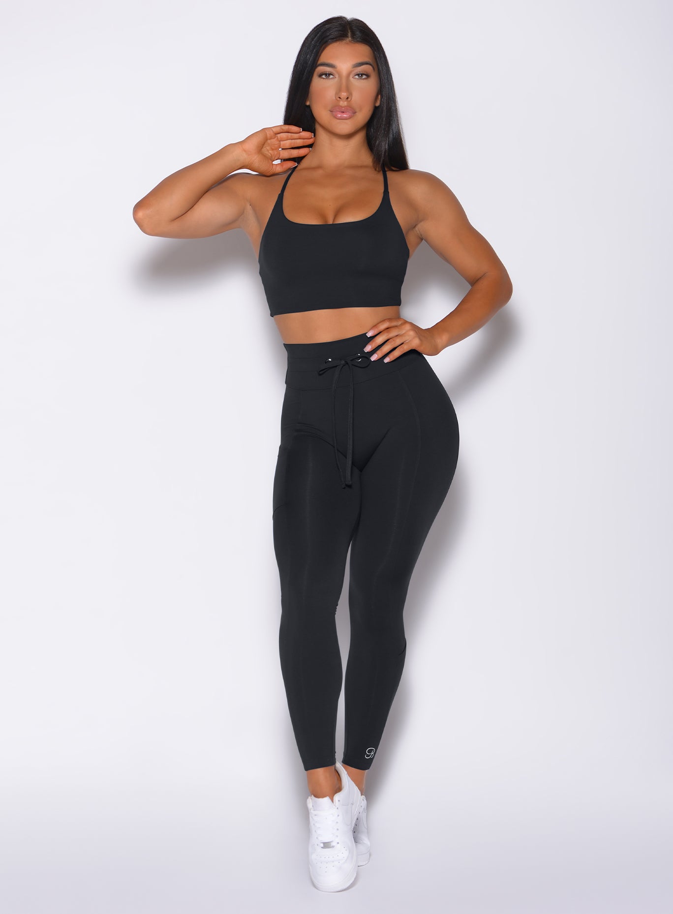 Front profile view of a model in our black empower leggings and a matching sports bra