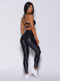 Right side profile view of a model in our gloss black leggings and a matching bra