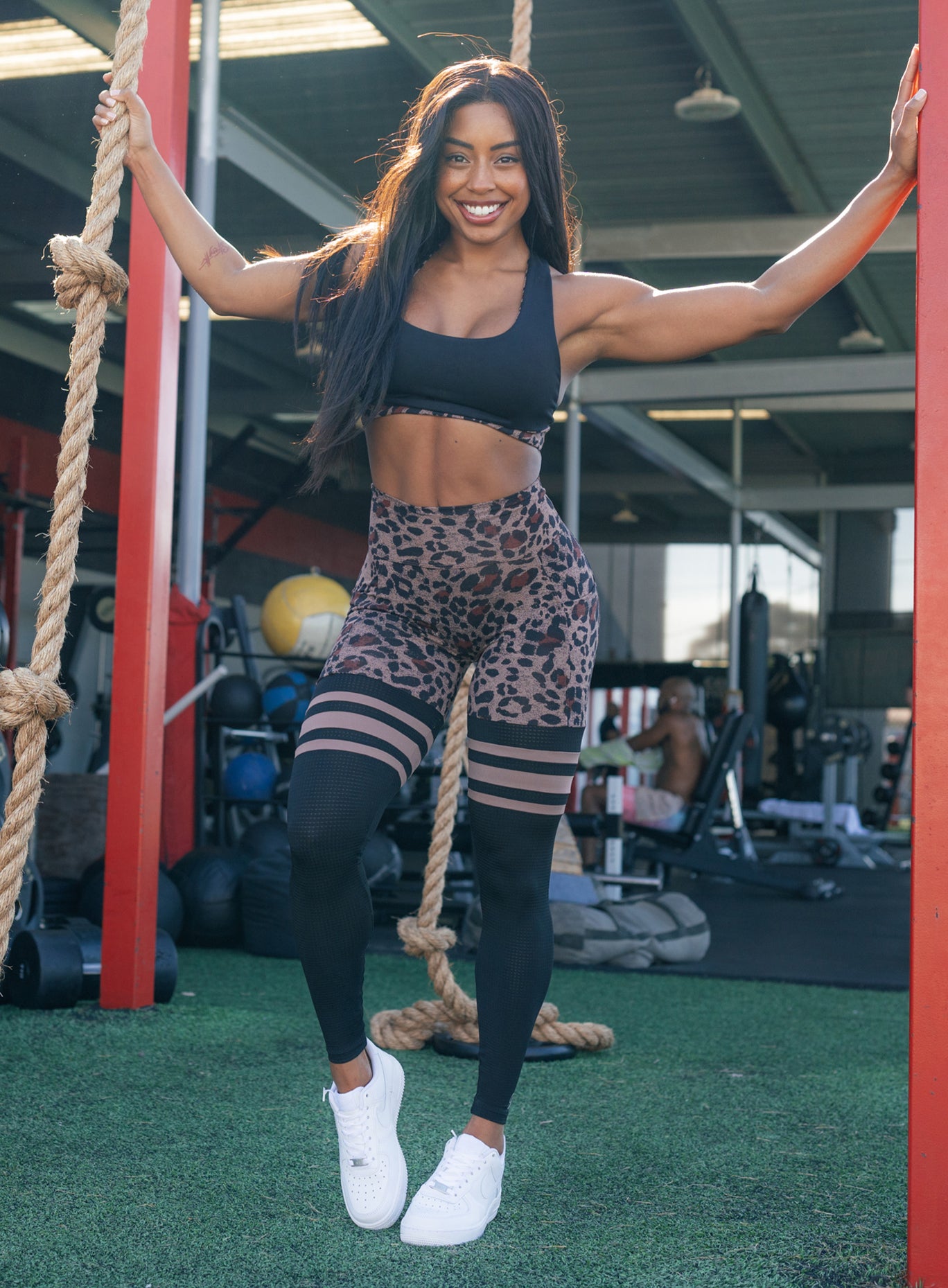 Front profile picture of a model wearing our scrunch thigh high in brown leopard color and a black sports bra 
