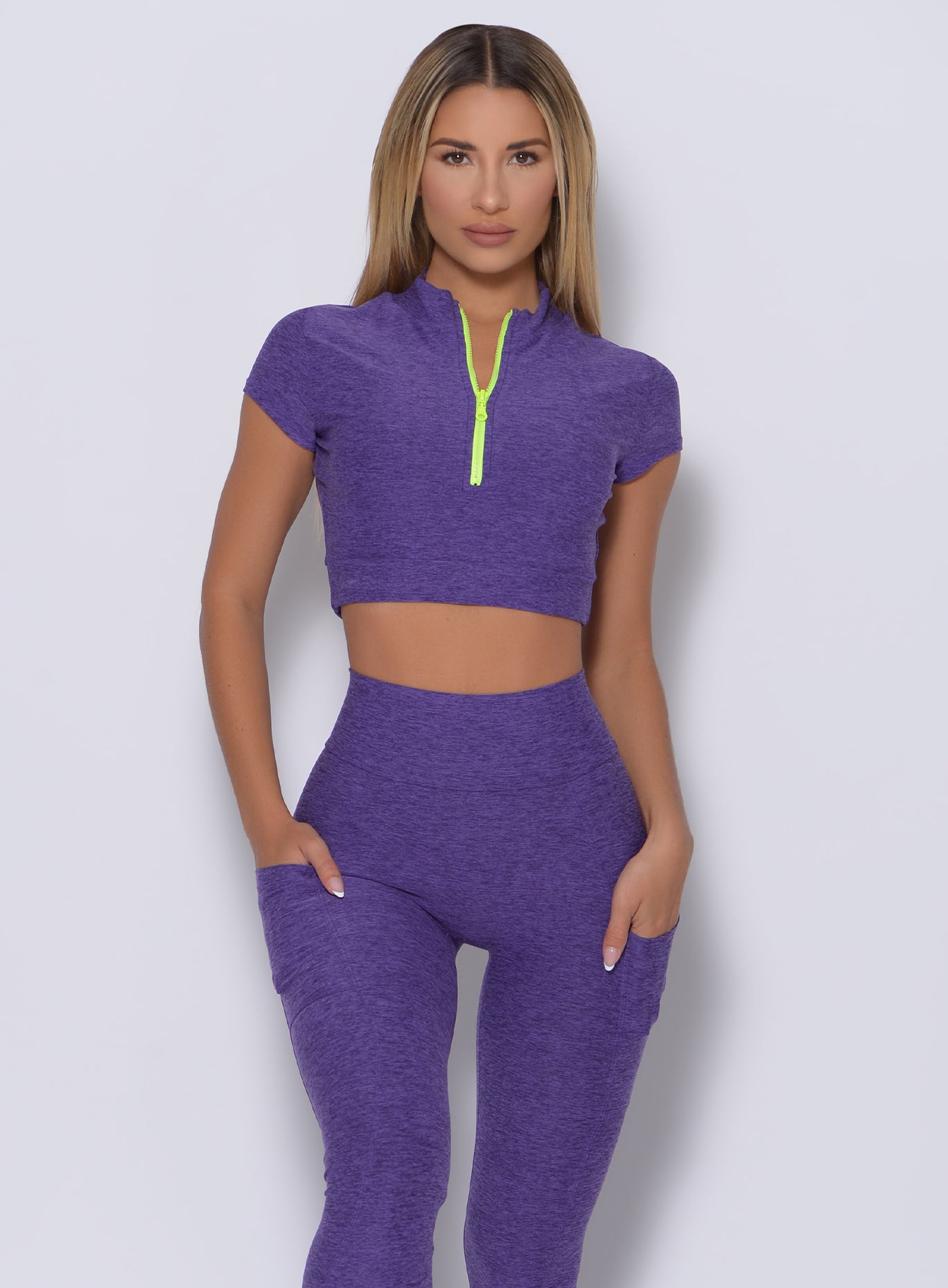 Model facing forward wearing our neon zip top in iris color and a matching leggings
